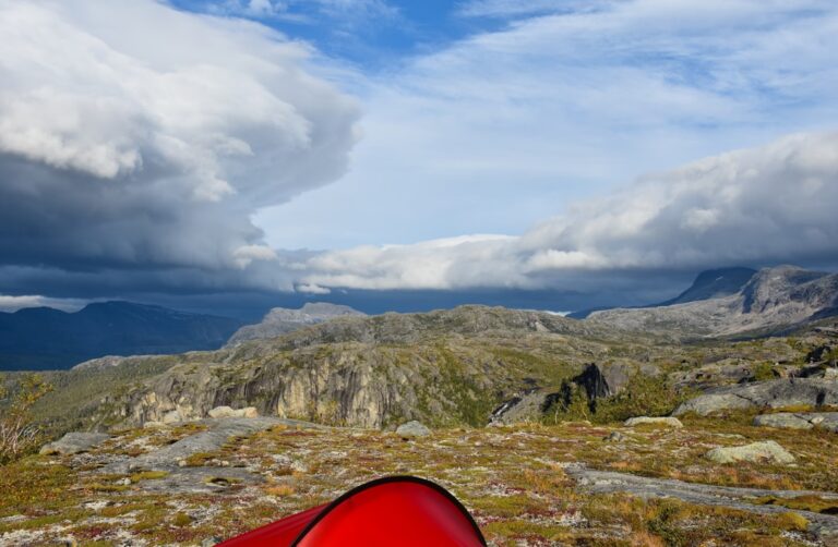 Red tent on rocky mountain landscape under cloudy sky
