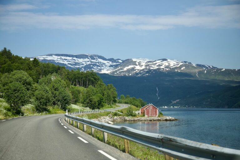 a road next to a body of water with mountains in the background